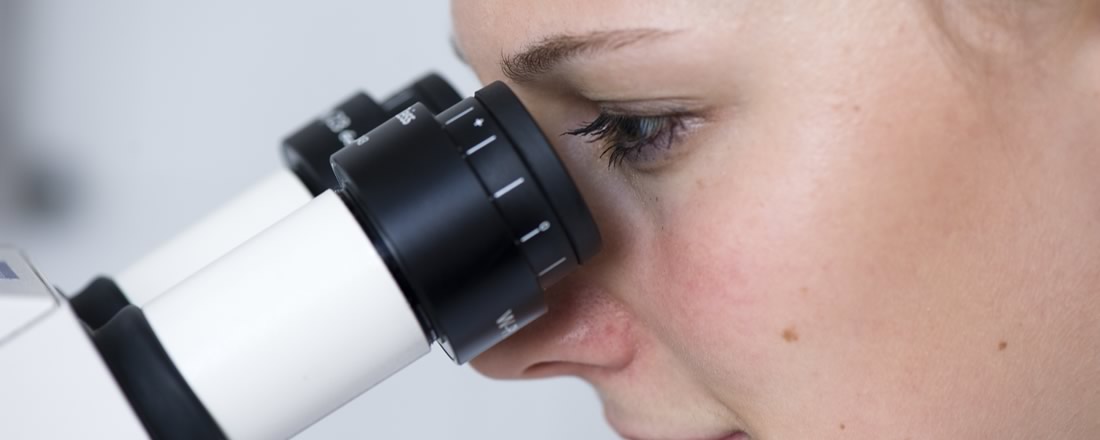 Eine Wissenschaftlerin blickt ins Mikroskop
